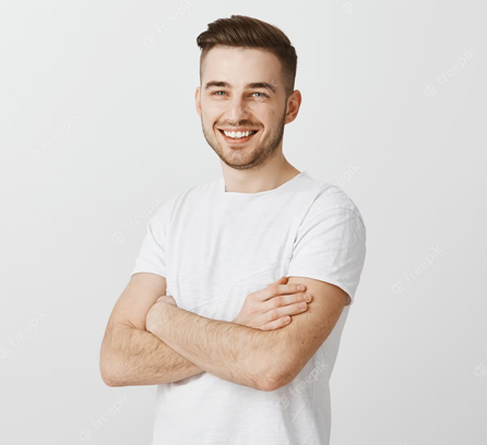 A young man with a cheerful expression stands with his arms crossed, posing for a portrait on a white background.