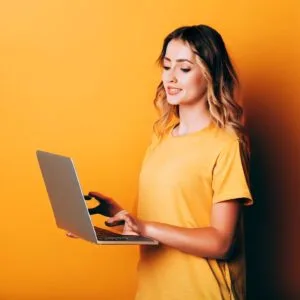 A lady holding a laptop and typing something.